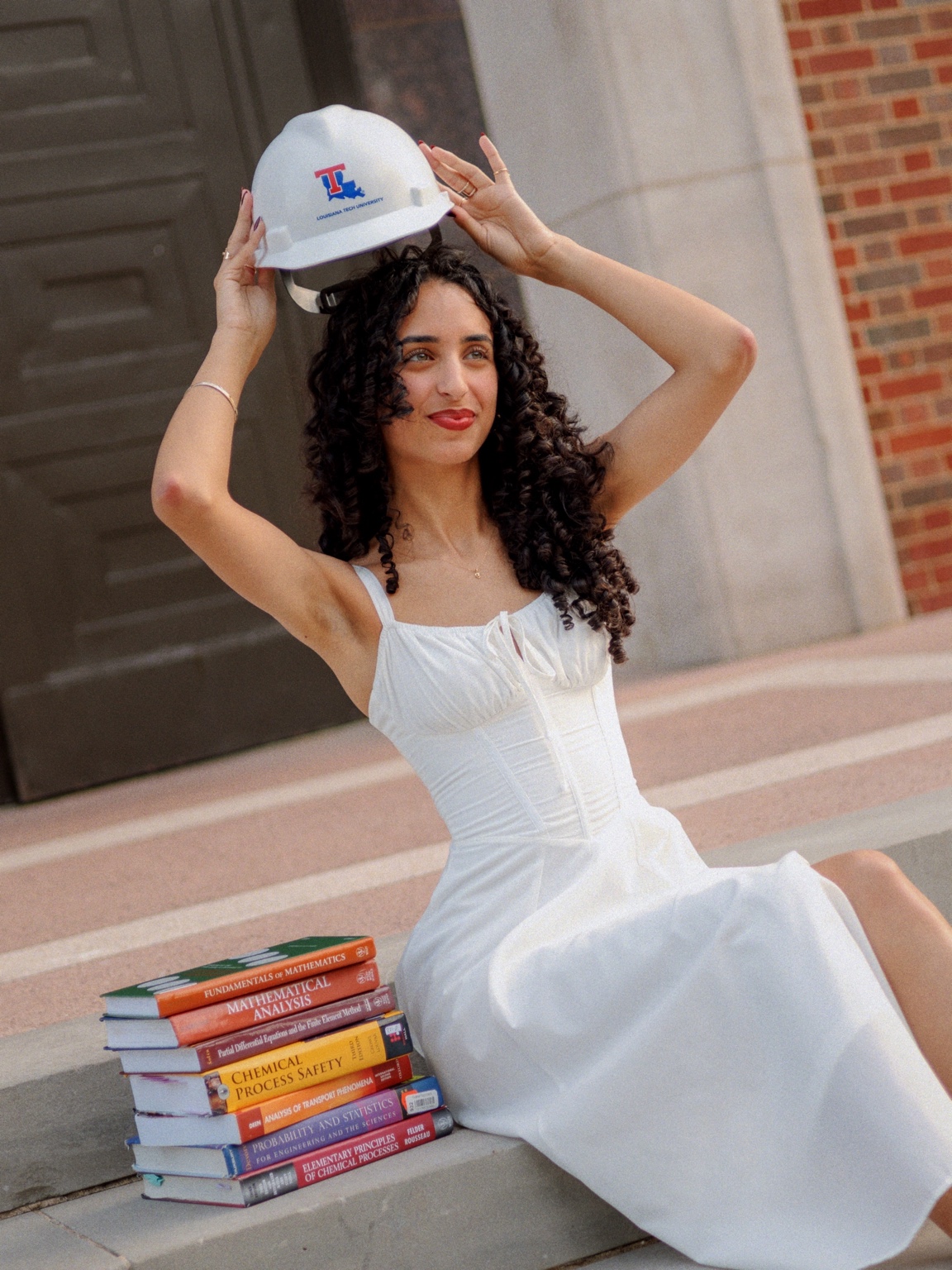Graduate sitting with a stack of books